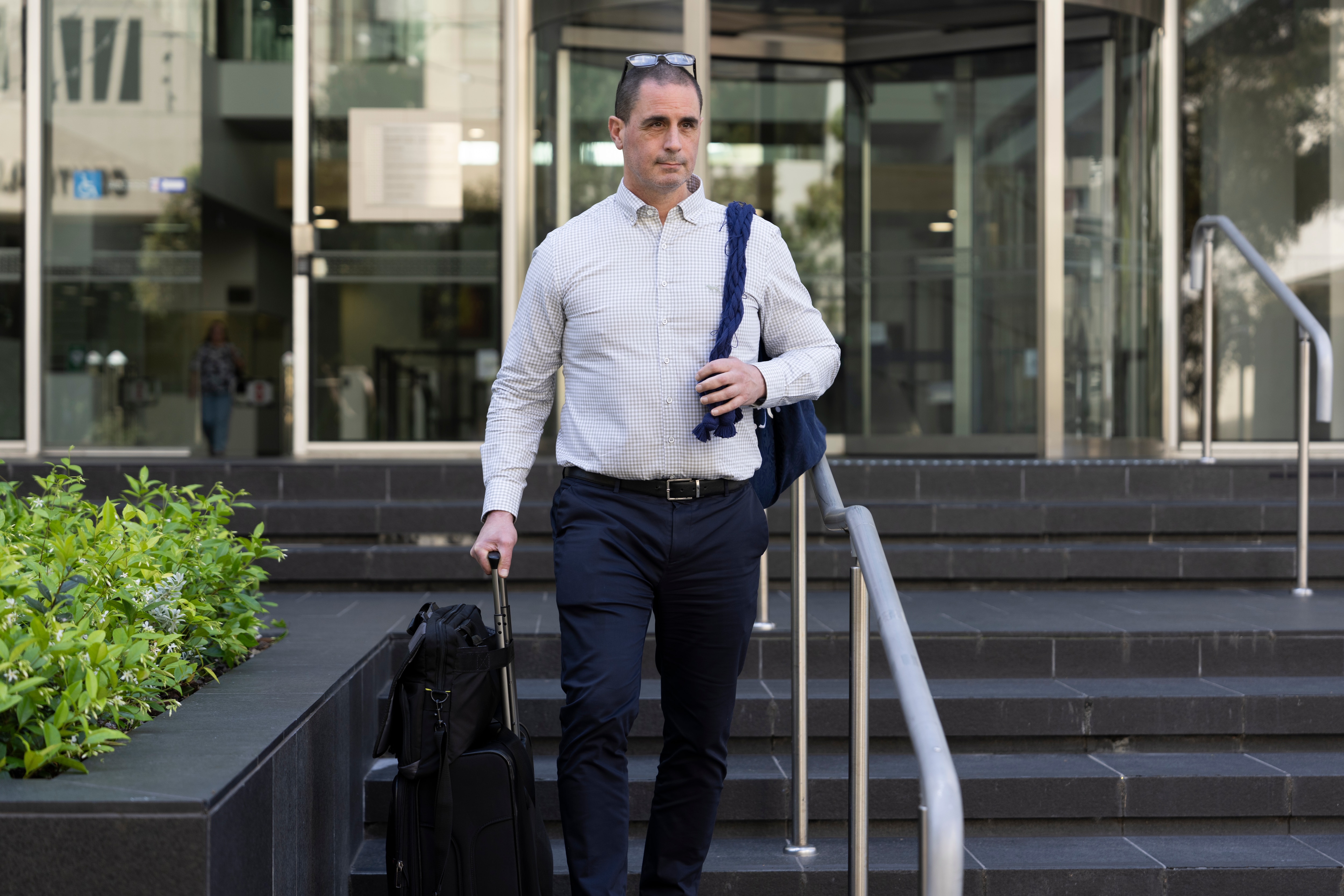 A man with his backpack on the back walks out a court building. 