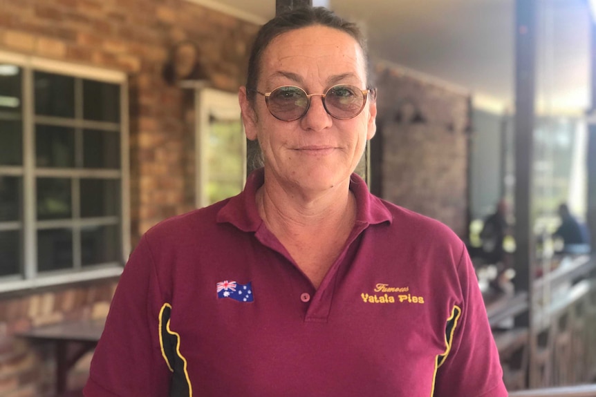 A woman wearing a maroon shirt looks into the camera.