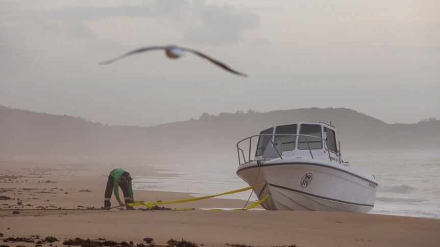 police secure an empty boat on a beach