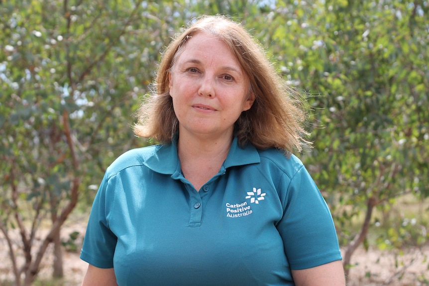 A mid-shot of a smiling woman wearing a turquoise polo shirt.