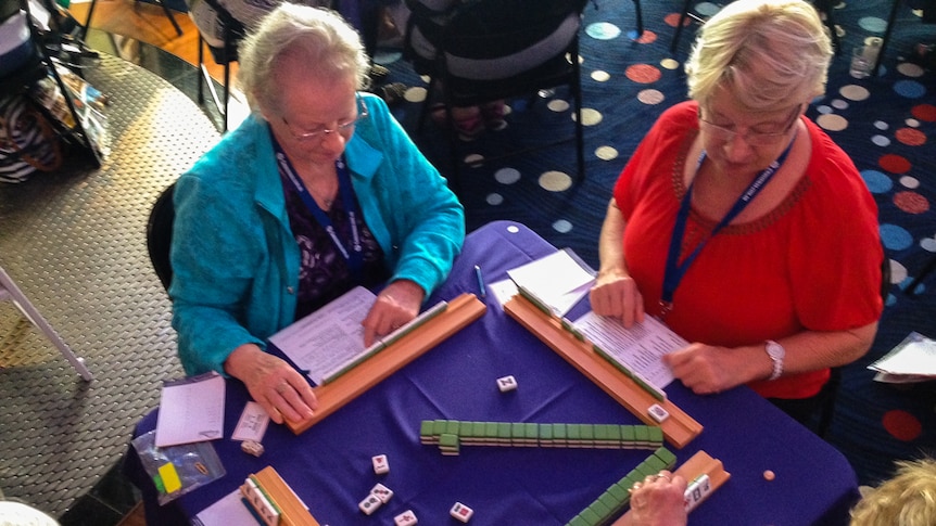 Four players play mahjong at a table aboard a cruise ship.