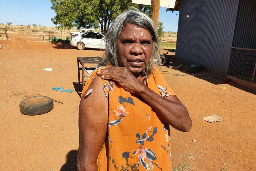 An Aboriginal woman holds her sleeve up, showing where she had received her COVID-19 vaccine.