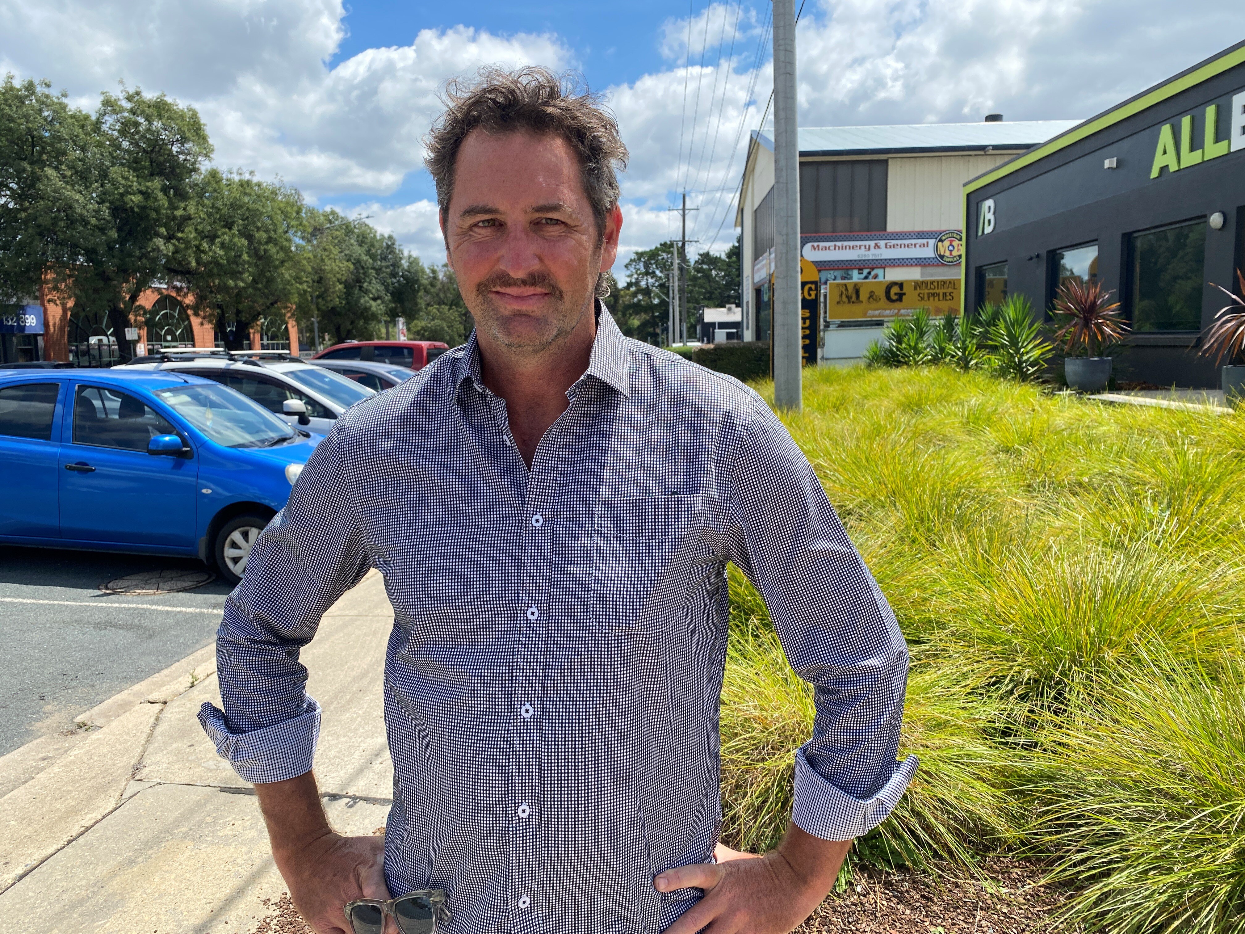 A man with hands on hips on a suburban street