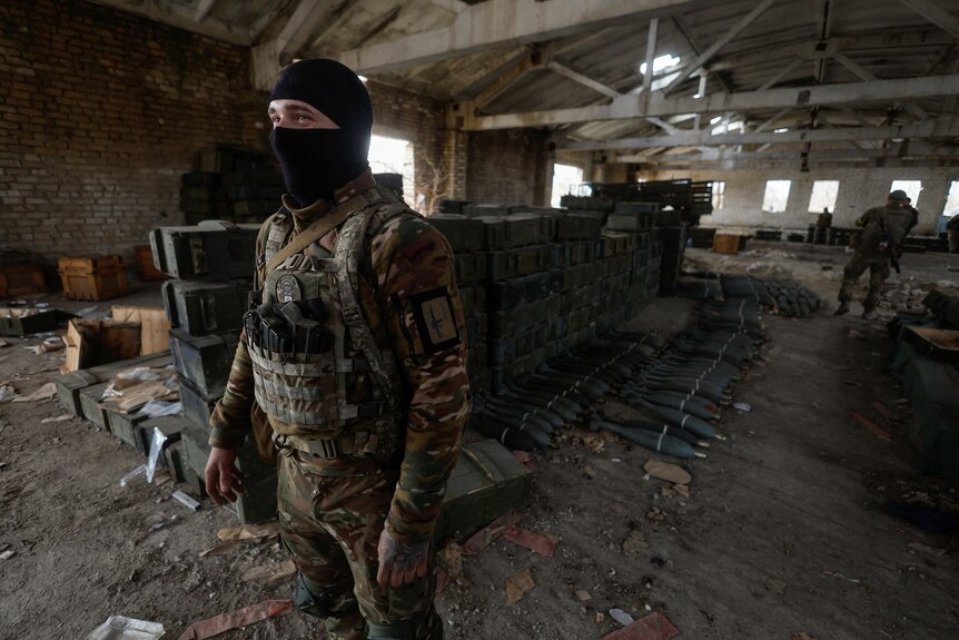 A Ukrainian soldier stands next to captured Russian ammunition in the village of Blahodatne.