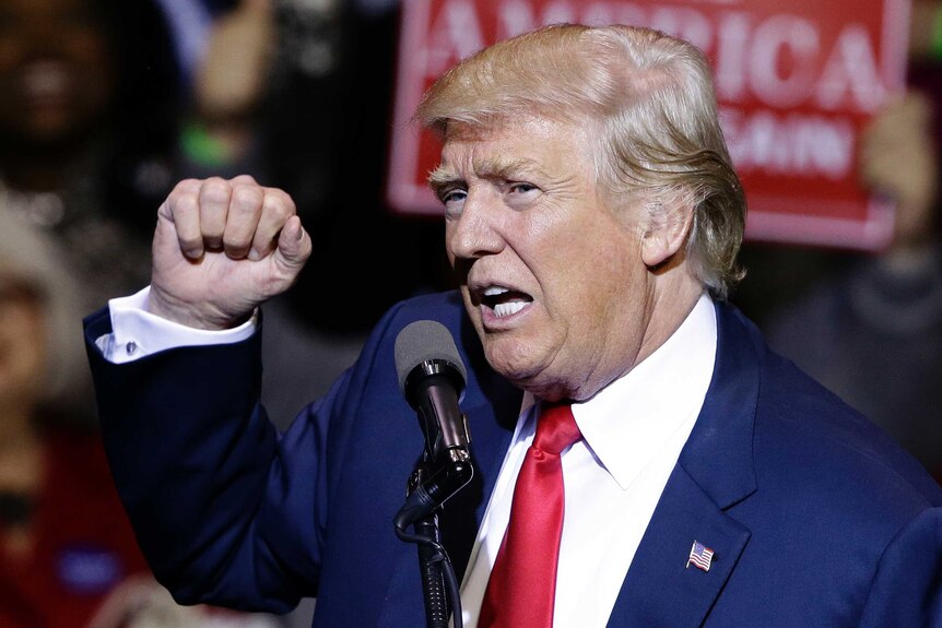 Donald Trump holds up a clenched fist during a speech.