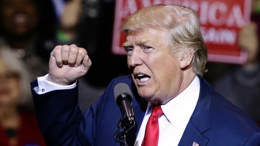 Donald Trump holds up a clenched fist during a speech.