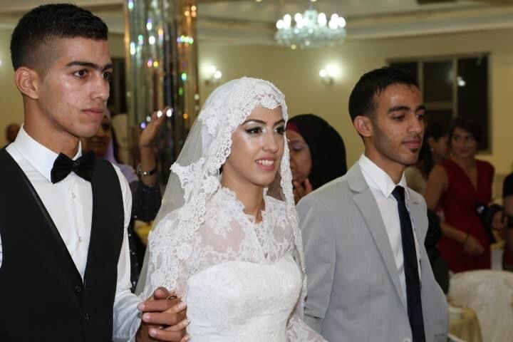 Aseel wears a white dress and veil, her husband is in a suit.