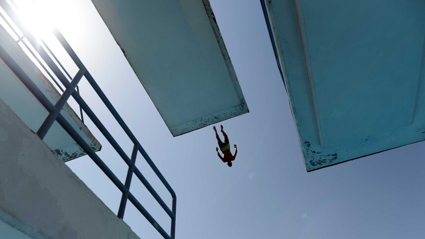 A man jumps into a pool to cool off.