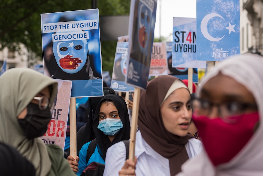 Women in hijabs protest holding placards reading 'stop the Uyghur genocide'