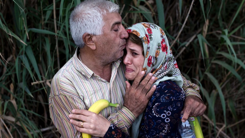 A migrant woman cries as she is embraced by a relative upon their arrival on the shores of the Greek island of Lesbos after crossing the Aegean Sea from Turkey on a dinghy