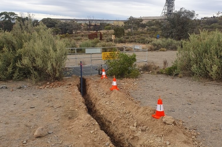 A long vertical hole surrounded by cones with a blue pipe coming out of it 