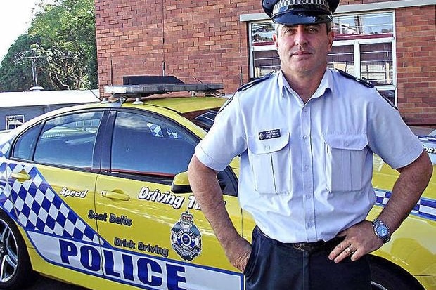 A policeman standing in front of a police car.