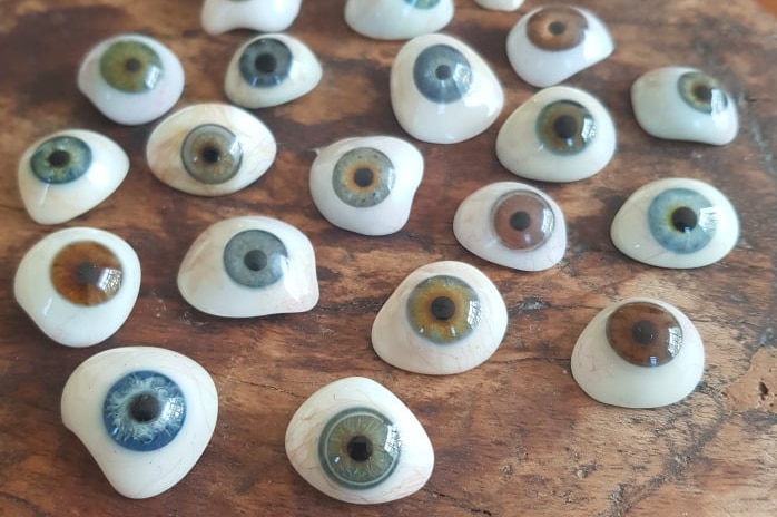 22 fake eyeballs with different coloured irises on a timber tabletop.