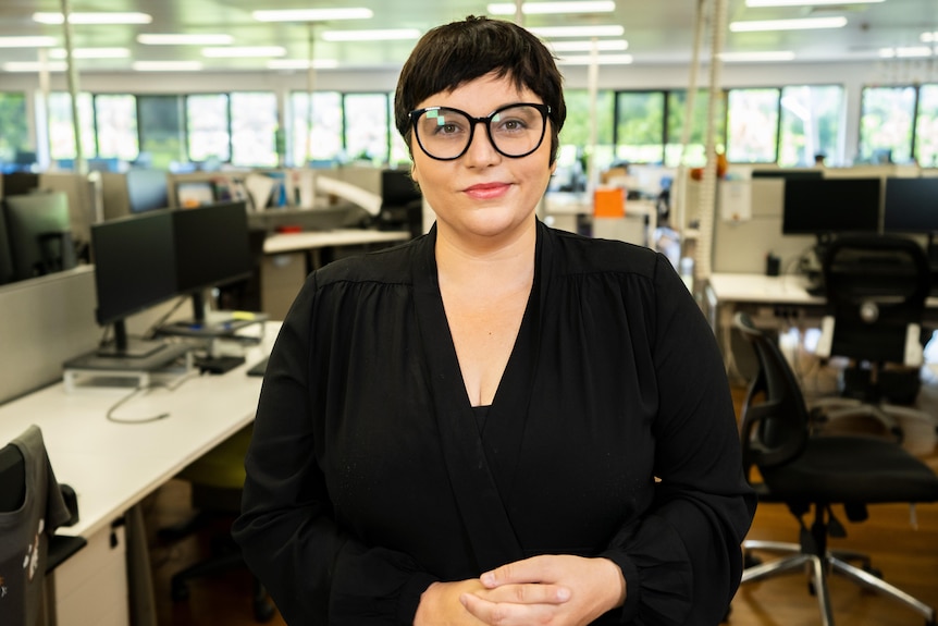 Erin Turner wearing professional clothing and thick-rimmed glasses, smiling in a portrait taken in an office.