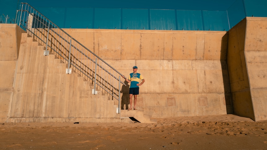 a man standing in front of a big wall along a beachfront
