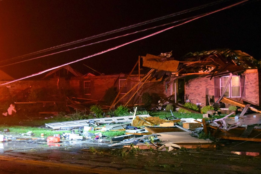 A picture at night of a building rubble destroyed by a tornado.