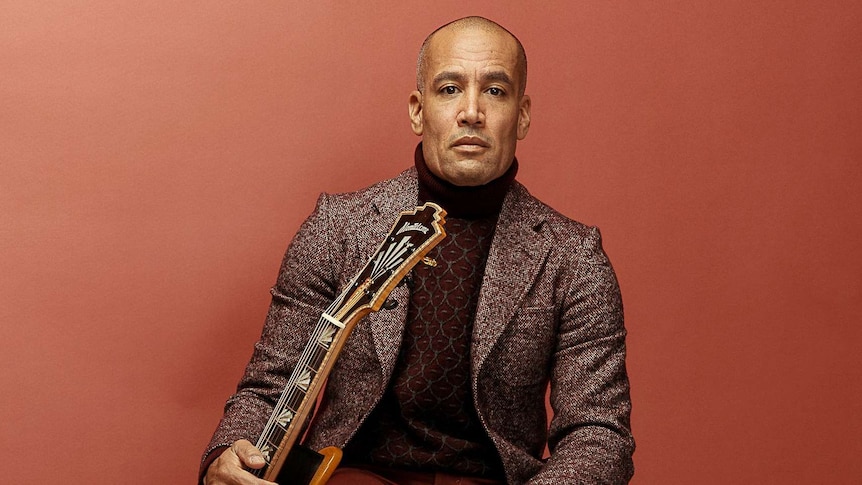 Image of Ben Harper looking into the camera while holding a lap steel guitar