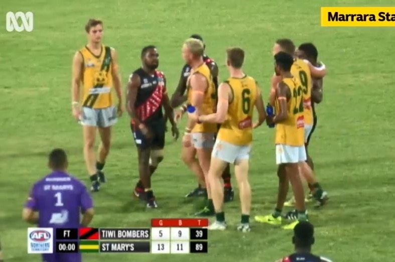 A group of Aussie Rules players stand around after a scuffle breaks out.