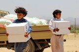 Displaced Yemeni children carry boxes of aid donated by UNICEF