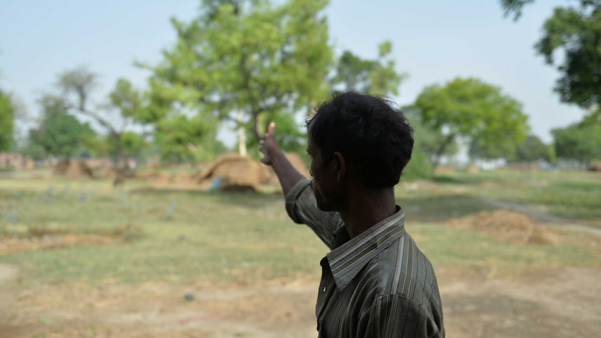 The father of one of the victims points towards a tree where his daughter was found hanged