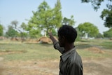 The father of one of the victims points towards a tree where his daughter was found hanged