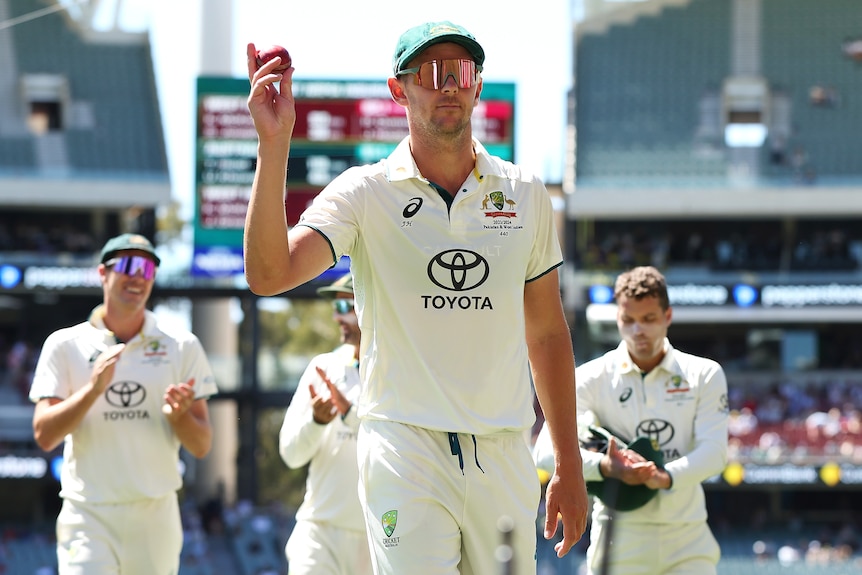 Josh Hazlewood holds the ball up as he leaves the field ahead of his teammates