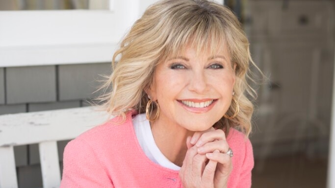 Photo of a blond-haired woman wearing a pink cardigan, smiling