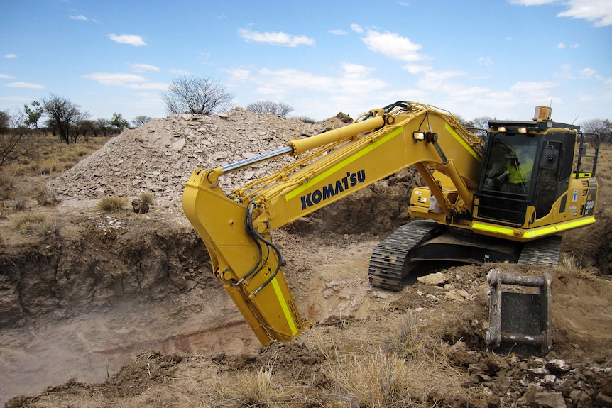A digger operating in a dirt patch