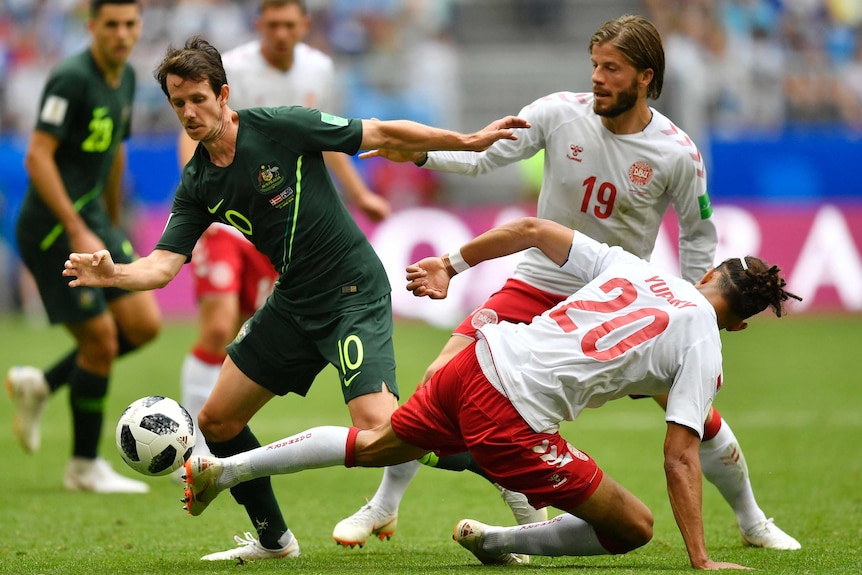 Robbie Kruse is challenged by two Danish players