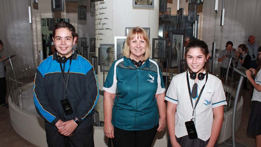 History teacher with her students inside exhibition surrounded by old war photographs