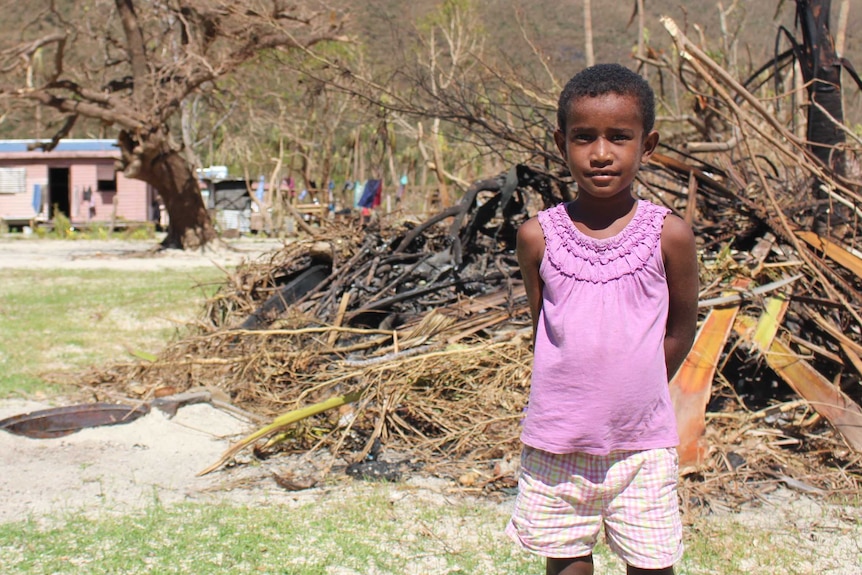 Girl stands in front of rubbish