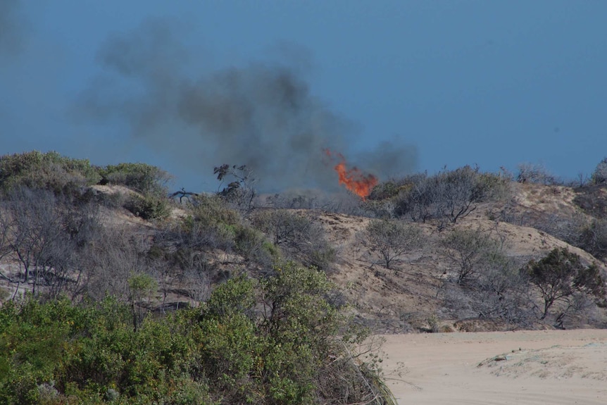 Flames rise up over sand dunes at a bushfire at Secret Harbour.