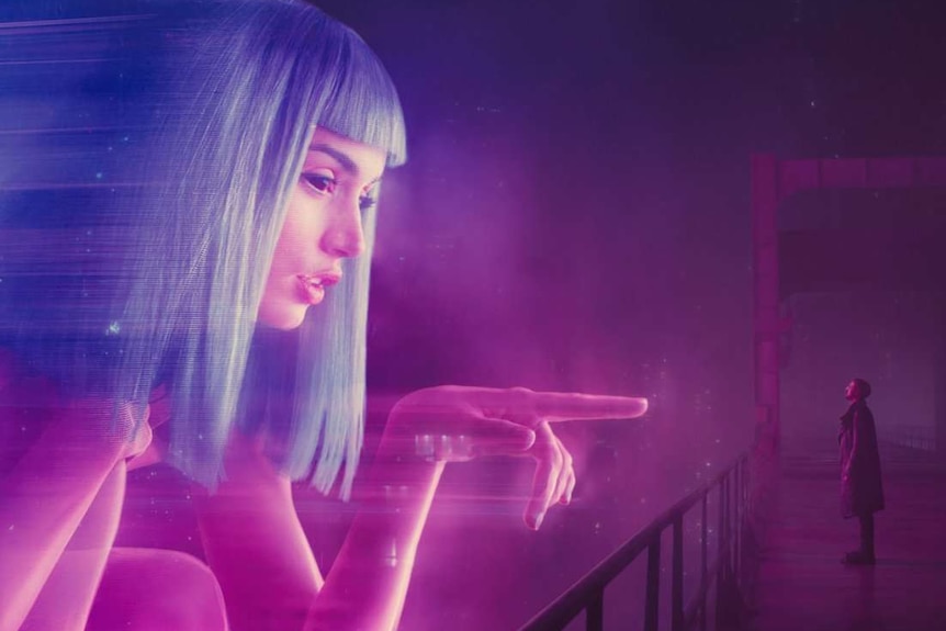 Still image from 2017 film Blade Runner of Ana de Armas' character as a large scale hologram interacting with Ryan Gosling.