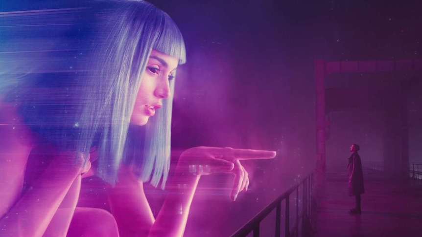 Still image from 2017 film Blade Runner of Ana de Armas' character as a large scale hologram interacting with Ryan Gosling.