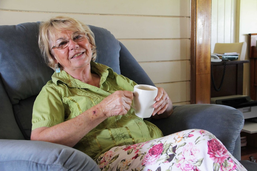 A woman in a lounge chair drinking a cup of tea.