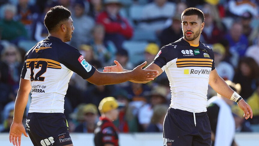 Two Brumbies Super Rugby players shake hands during a match.