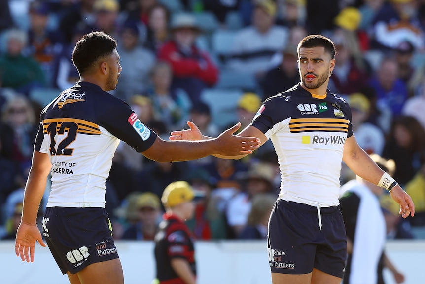 Two Brumbies Super Rugby players shake hands during a match.