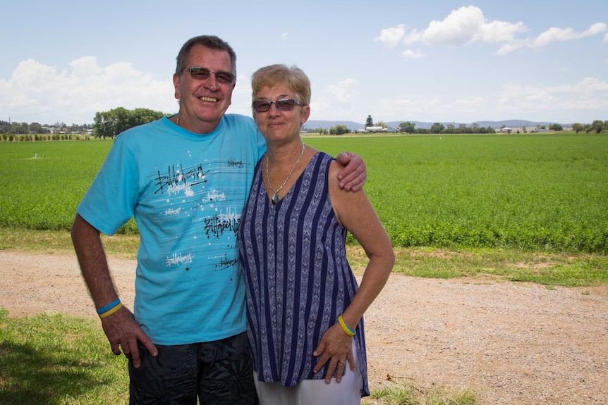 John and Cindy McCowan stand next to a paddock.
