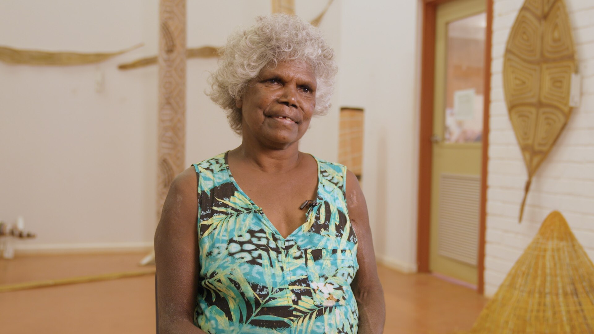 Freda Wayartja Ali, a Burarra woman in her 60s with short curly grey hair, wearing a pale blue singlet in a gallery.