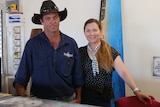 A man and woman stand behind a bar.