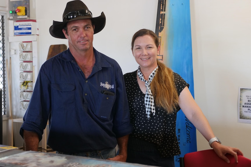 A man and woman stand behind a bar.