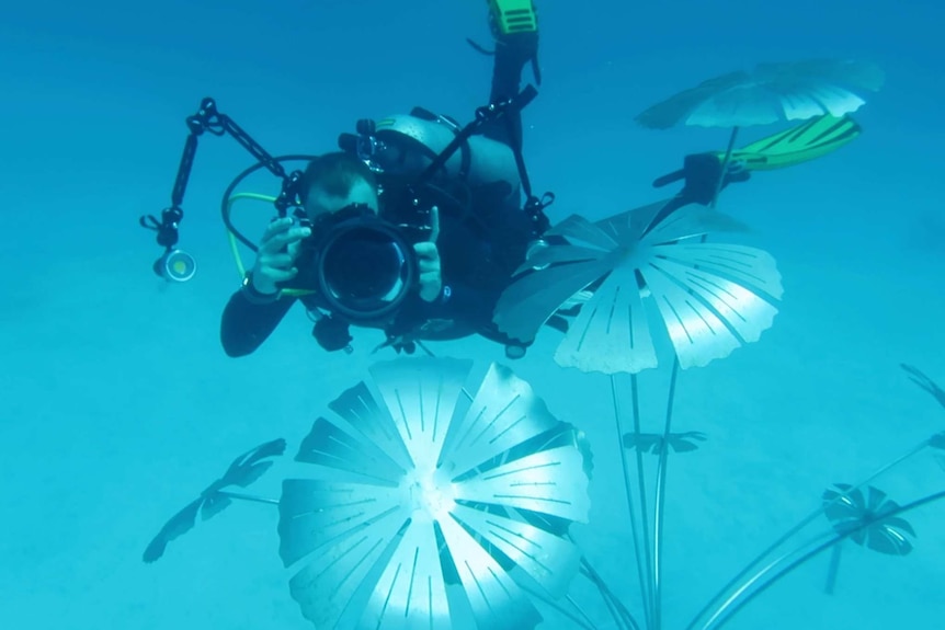 A diver photographs an underwater sculpture at the Museum of Underwater Art.