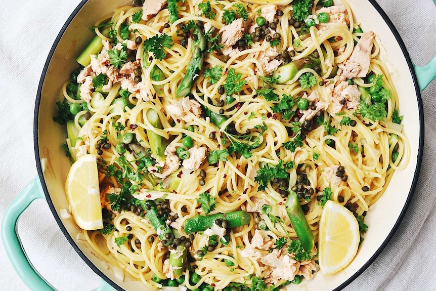 A pan of one pot spaghetti with parsley, capers, tuna, lemon, peas and asparagus, illustrating our recipe.