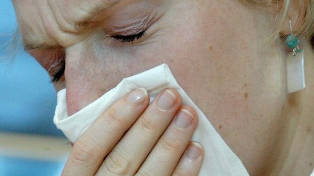 A woman sneezes during a bout of flu.