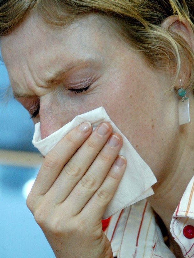 A woman sneezes into a tissue