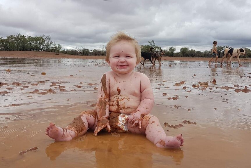 Eight-month-old Riley James Berger plays in the mud.