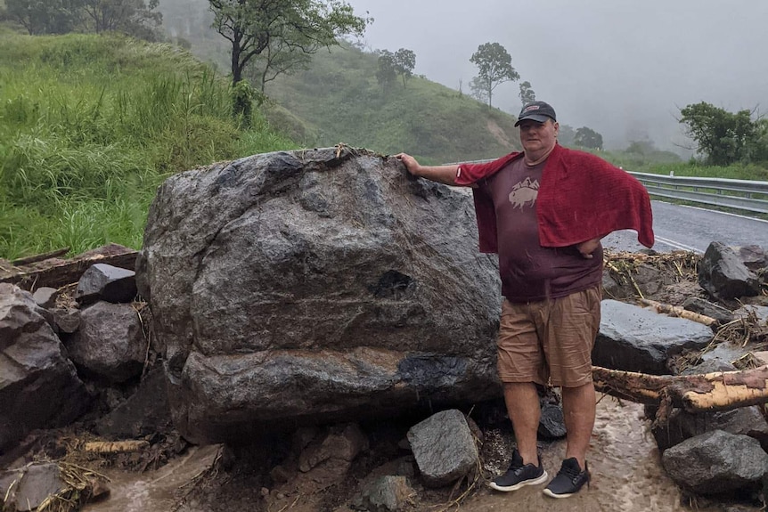 Dale Fortescue stands next to rocks and boulders in a flooded area.