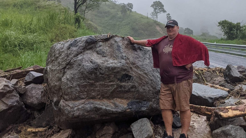 Dale Fortescue stands next to rocks and boulders in a flooded area.