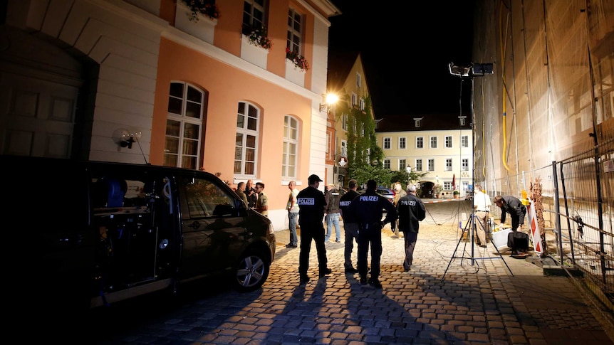 Police stand under lights set up near secured area