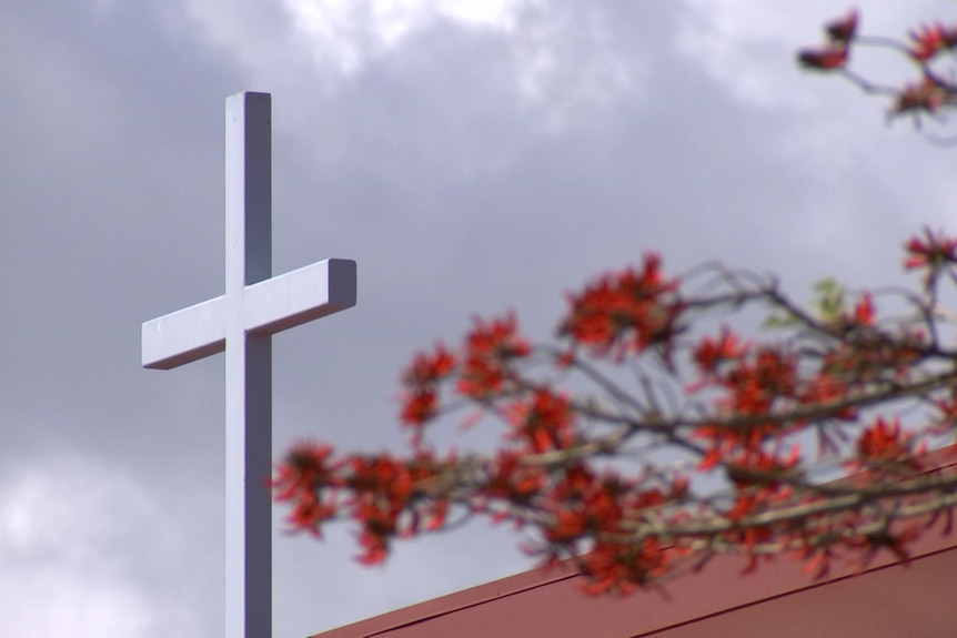 A Christian cross towering over a roof.